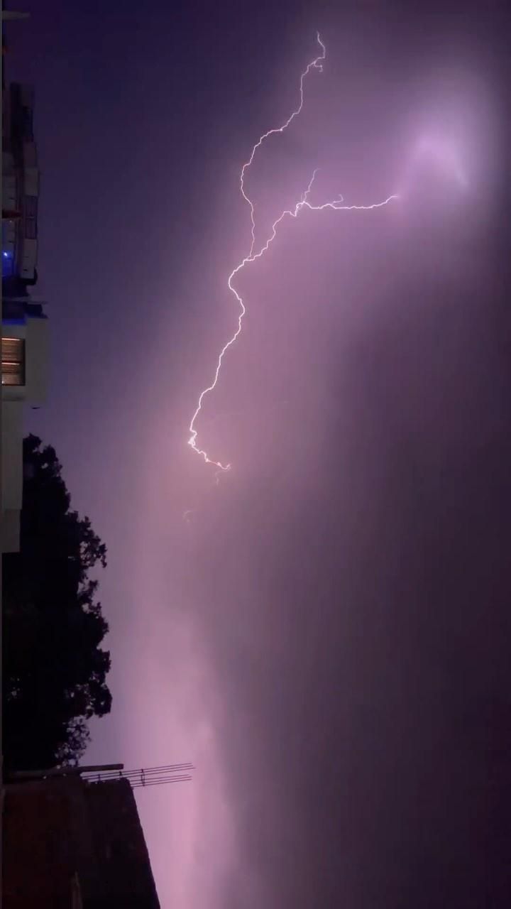 काले बादलों, तेज हवा और बारिश के बीच सड़क और पेड़ों का दृश्य, जो मौसम के खराब हालात को दर्शाता है