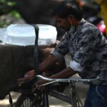 तेज धूप और गर्म हवाओं के बीच सड़क पर चलते लोग, जो हीटवेव की स्थिति को दर्शाता है