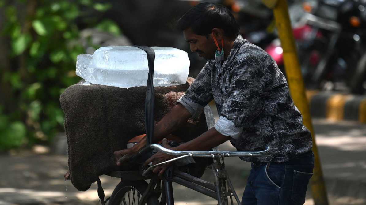 तेज धूप और गर्म हवाओं के बीच सड़क पर चलते लोग, जो हीटवेव की स्थिति को दर्शाता है